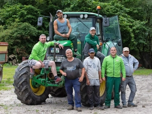 Eine Gruppe von sechs gut gelaunten Bauern in passender grüner Arbeitskleidung posiert mit einem grünen Traktor in der grünen ländlichen Umgebung des Cassenhofs und zeigt ihre Kameradschaft und eine kurze Pause von ihrer täglichen Arbeit. - Ihr Landhaus Scherrer aus Hamburg