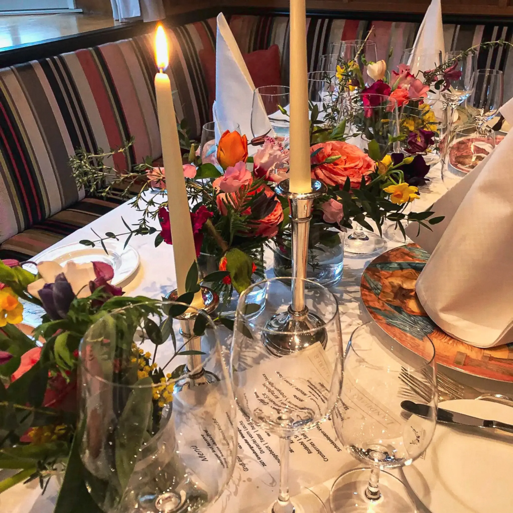 Ein elegant gedeckter Esstisch mit brennenden Kerzen, frischen Blumenarrangements, Kristallgläsern, feinem Porzellan und aufwendigem Silberbesteck lädt zu einer gehobenen und intimen Zusammenkunft bei Hochzeiten ein. - Ihr Landhaus Scherrer aus Hamburg