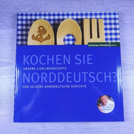 Ein Kochbuch mit dem Titel "Kochen Sie norddeutsch?" in weißer Schrift auf blauem Einband, mit Untertitel und einem Bild des Küchenchefs Heinz O. Wehmann, der auf einem blauen - Ihr Landhaus Scherrer aus Hamburg