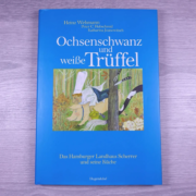 Ein Kochbuch – Ochsenschwanz & weißer Trüffel von Heinz O. Wehmann und anderen, mit einer farbenfrohen Illustration eines Kochs und zweier Tiere beim Kochen. - Ihr Landhaus Scherrer aus Hamburg