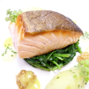Die Fisch-Spezialität Faröer Lachs wird auf den Punkt in einer Pfanne angebraten und anschließend auf den jungen Spinat aufgesetzt. Der Spinat ist optisch richtig grün und hat einen guten Biss. Aromatisch passend wird Kartoffelstampf und eine Senf-Sauce serviert. Als i-Tüpfelchen werden schmackhafte Senf-Saaten links und rechts mit platziert. - Ihr Landhaus Scherrer aus Hamburg